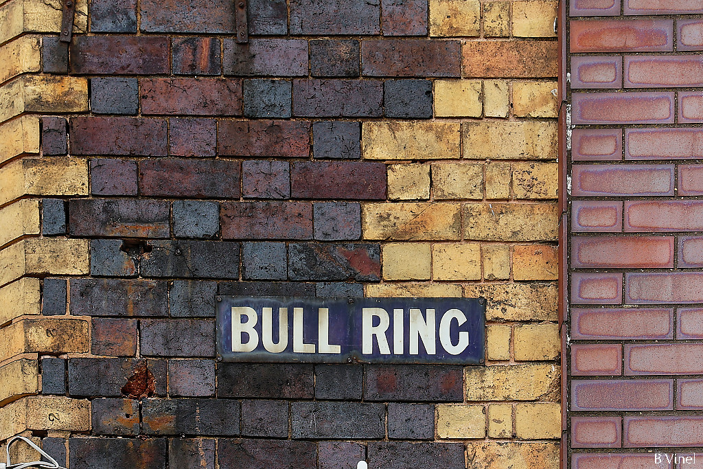Bull ring street sign on a brown, beige and red brick wall