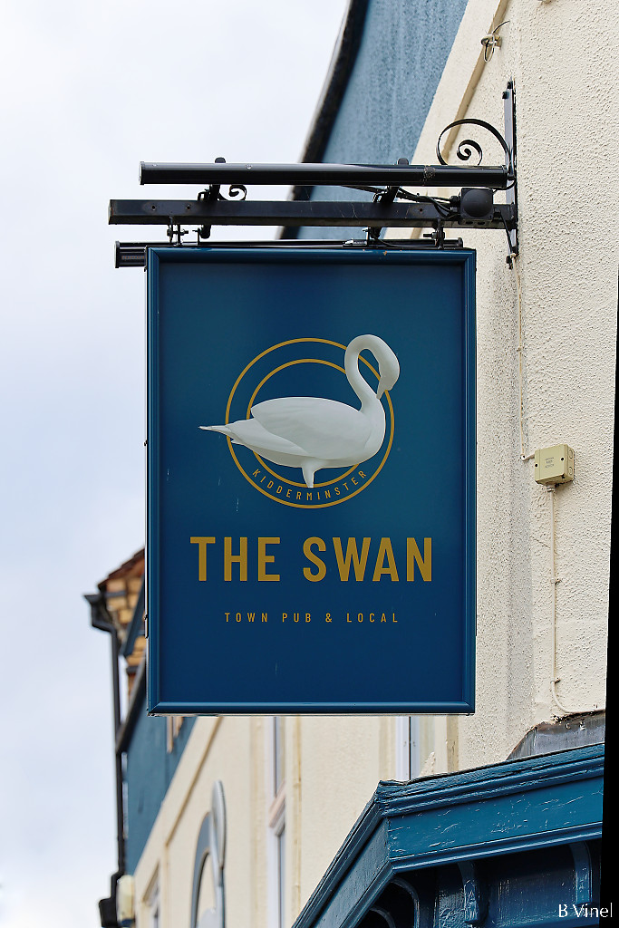 The Swan pub sign, with a white swan drawing, hanging from a cream wall