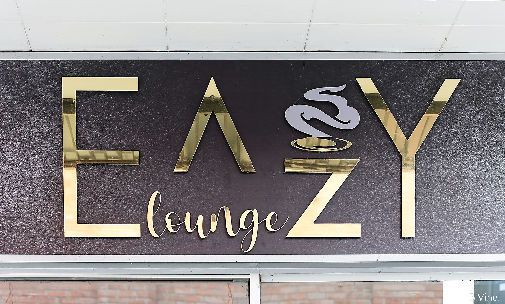 Easy Lounge sign with gold Greek style fonts on a black background