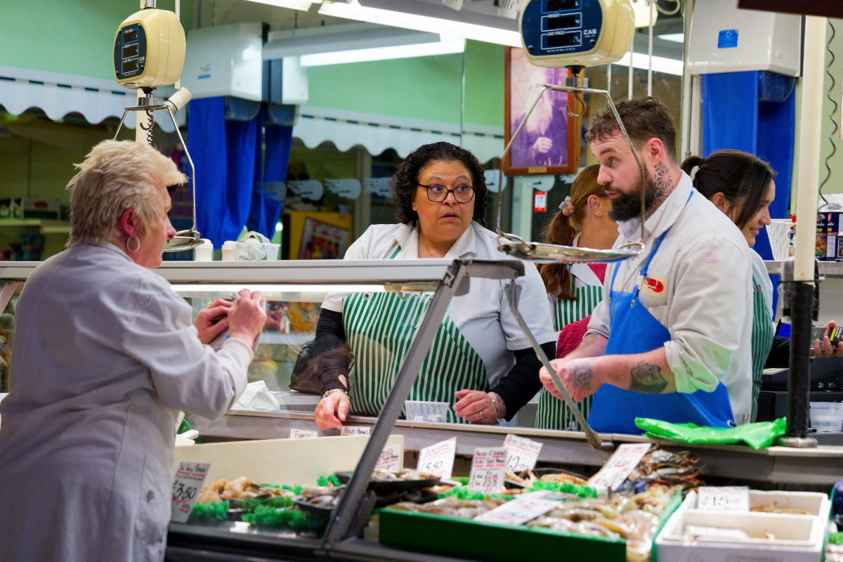 Two fishmongers and a customer are talking at the Bullring covered marketplace in Birmingham.