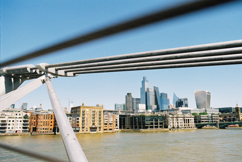 The City of London seen from the Millenium bridge with the structure of the bridge in the foreground