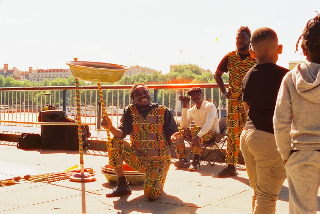 A plate spinning performer on the bank of the Thames river calling at passerby tourists