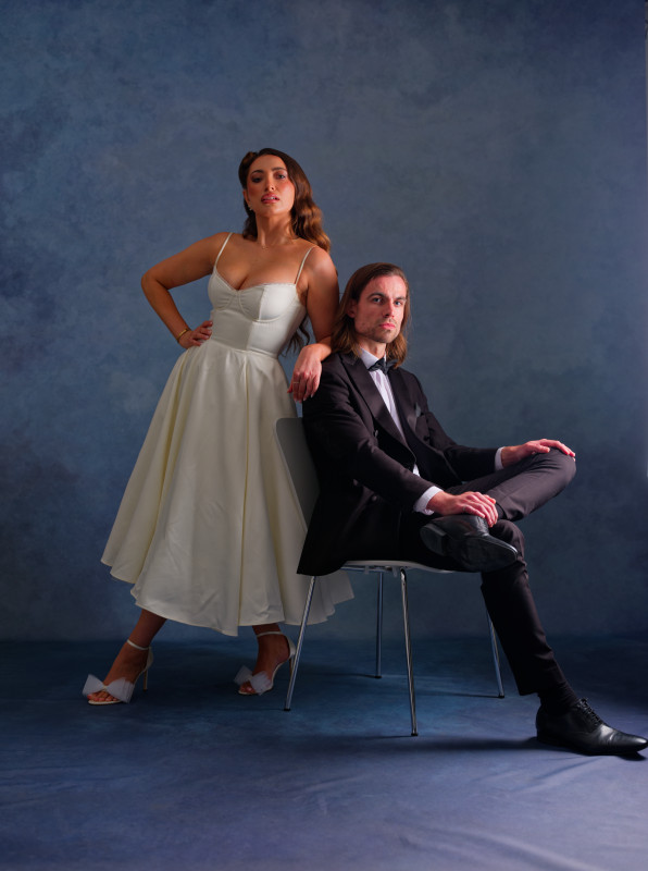 A bride and groom pausing with the groom seated